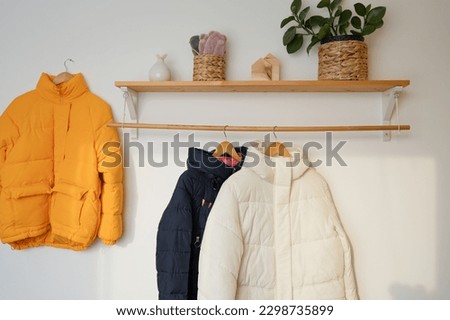 Winter clothes on a hanger in the room. A row of down jackets hang on a white background. Royalty-Free Stock Photo #2298735899