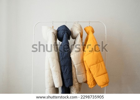 Winter clothes on a hanger in the room. A row of down jackets hang on a white background. Royalty-Free Stock Photo #2298735905