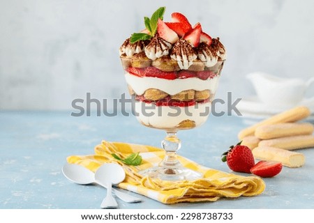 Strawberry tiramisu in a glass bowl on a blue background. Summer berry dessert trifle. Selective focus. Copy space Royalty-Free Stock Photo #2298738733
