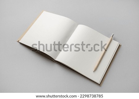 Blank open sketchbook and pencil on gray paper background. Responsive design template.