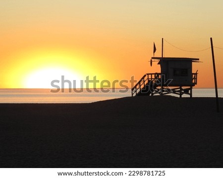               California sunset at the beach with a silhouette of a lifeguard station           