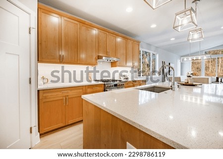 Home kitchen interior with island and bar stools hardwood floors granite and corion countertops white and wood tone cabinets large and spacious rooms Royalty-Free Stock Photo #2298786119