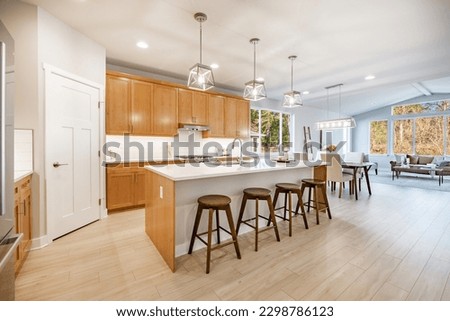 Home kitchen interior with island and bar stools hardwood floors granite and corion countertops white and wood tone cabinets large and spacious rooms Royalty-Free Stock Photo #2298786123