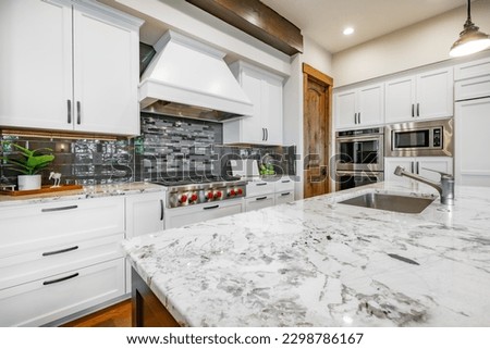 Home kitchen interior with island and bar stools hardwood floors granite and corion countertops white and wood tone cabinets large and spacious rooms Royalty-Free Stock Photo #2298786167