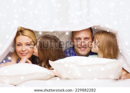 family, children, comfort, bedding and home concept - happy family with two kids under blanket over snowflakes background