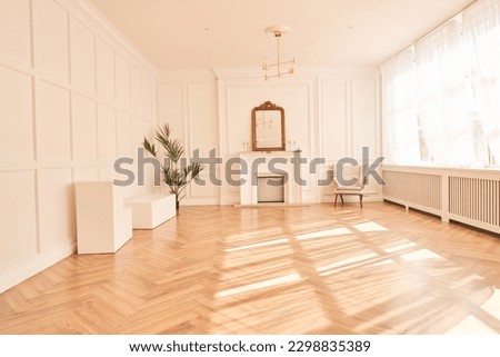 Bright interior with large windows and a fireplace in a classic style. Large living room with decor items. Beautiful parquet and copy space. Sunlight and shadows in the room. High quality photo