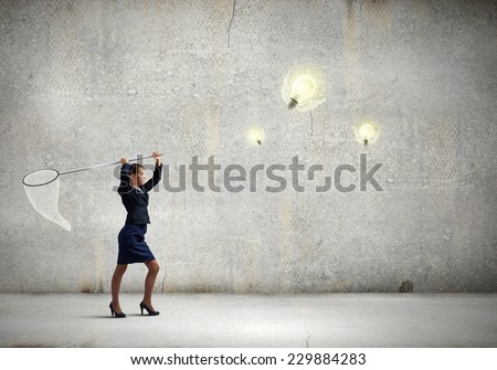 Young businesswoman catching light bulb with hoop