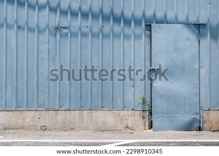 Warehouse building with a blue doorway and metal sheet wall. Indsutrial building and background object photo.