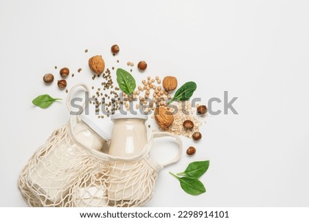 Variety of vegan plant based milk in zero waste mesh bag. Top view of lactose free milk based on nuts, legumes, oatmeal on white background Royalty-Free Stock Photo #2298914101