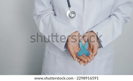 Doctor asian female specialist holding blue ribbon and stethoscope and Breast cancer awareness concept