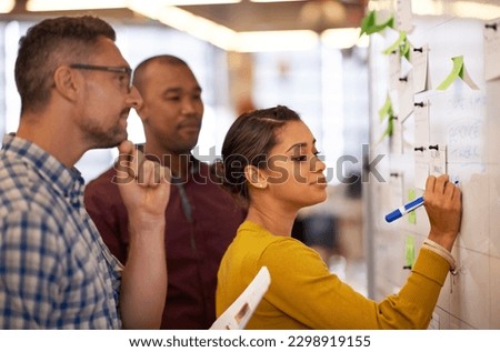 Collaboration, whiteboard and a business woman writing during a meeting for coaching in the office. Teamwork, training and presentation with a young female employee teaching her colleagues at work Royalty-Free Stock Photo #2298919155