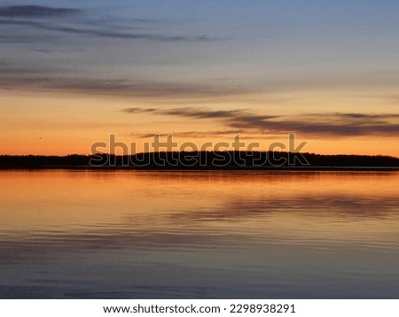 Colorful golden sunset over the lake and forest in the background. Leningrad region, Russia. Royalty-Free Stock Photo #2298938291