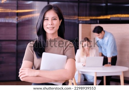 Smiling businesswoman holding laptop at office.
