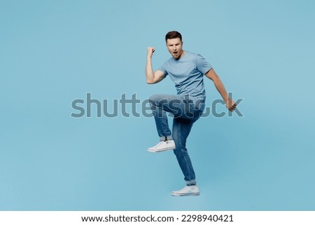 Full body side profile view young overjoyed excited happy man wear casual t-shirt do winner gesture look camera isolated on plain pastel light blue cyan background studio portrait. Lifestyle concept Royalty-Free Stock Photo #2298940421
