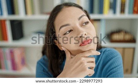 Young beautiful hispanic woman thinking at university classroom