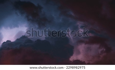 A horizontal view of the clouds and lightning in the sky. The photo has pink and blue tones.