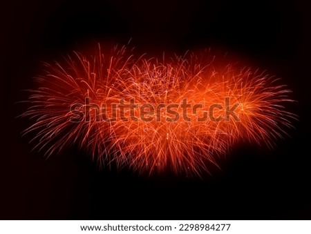 Beautiful red fireworks display lights up the sky with dazzling display during New Year celebration. Abstract colored fireworks background with copy space. Celebration and anniversary concept