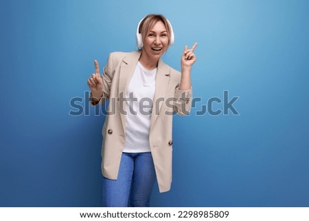 optimist cheerful young woman in a business jacket listens to the radio with headphones