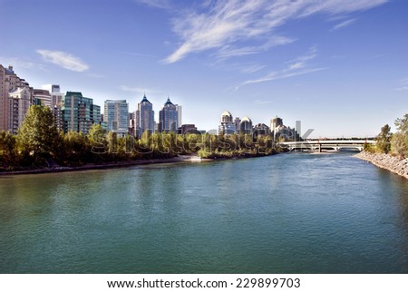 A pedestrian bridge across  Bow River in Calgary with skyscrapers in the background.