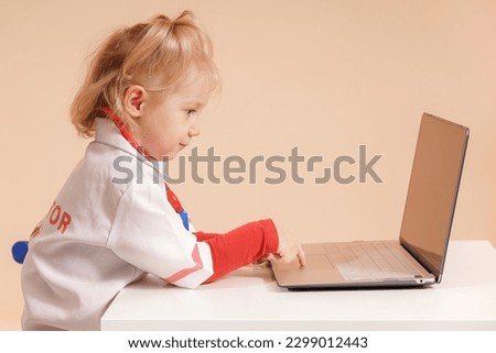 A little girl in doctor's clothes takes notes on the computer, the medicine 