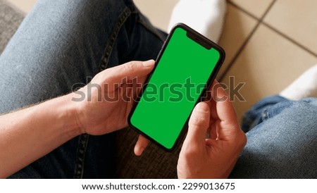 Holding a Green Screen Smartphone on the Couch at Home