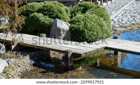 Wooden bridge over a small stream in a Japanese garden. The road is paved with stones and pebbles. Only natural natural materials. Royalty-Free Stock Photo #2299017921