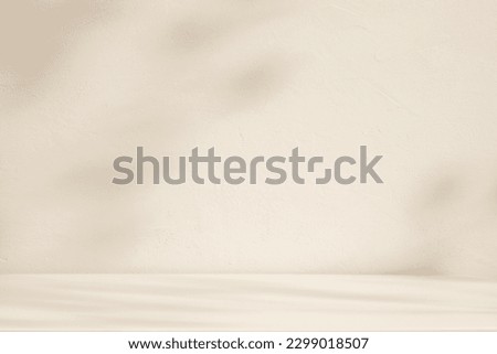 Light beige or cream stone background with blurred leaf shadows