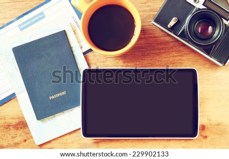 close up of top view image of tablet with empty screen, old camera, passport and flight boarding pass.