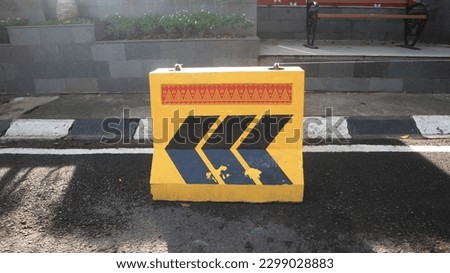 horizontal road markings. highway concrete barrier on the road, vehicle collision lane separator yellow color with black stripes, yellow and black concrete barrier blocking the road