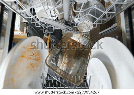 putting dirty greasy dishes into dishwasher. inside view Royalty-Free Stock Photo #2299034267