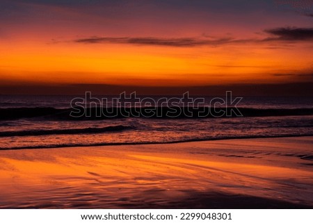 Amazing sunset at Seminyak Beach with red sky, and wet sand reflecting sky, Bali, Indonesia