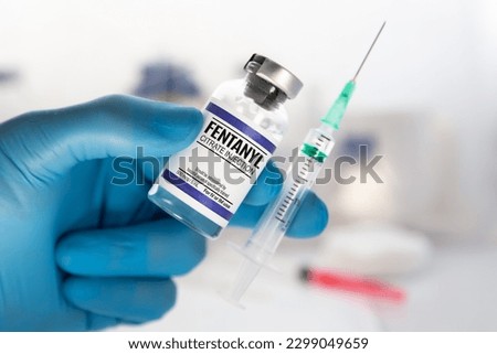 Professional with vial and injection of dose of Fentanyl Citrate Solution for analgesic treatment. Doctor holding injection of medication of Fentanyl is opioid used to palliate pain or for anesthetic Royalty-Free Stock Photo #2299049659