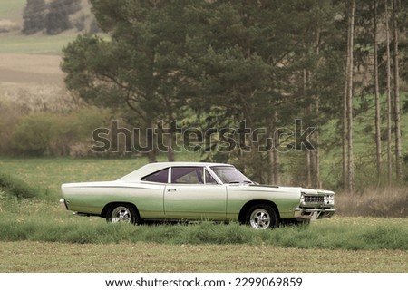 Classic American oldtimer vintage muscle car of the 1960s - 1970s on a country road on a sunny summer day. Royalty-Free Stock Photo #2299069859