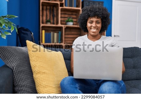 African american woman using laptop sitting on sofa at home
