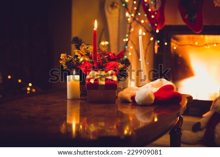 Toned photo of burning candles, fireplace and gift box at christmas eve