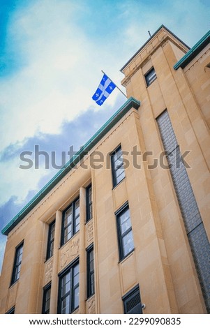 Quebec Provincial Flag called the Fleurdelisé, or lily-flowered, with a white cross on a blue background, and four white lily flowers, hanging at the top of downtown building in Quebec City, Canada