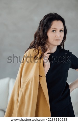stands a woman in a yellow jacket and black clothes. portrait of a woman. High quality photo