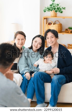 Grandpa taking pictures of baby and family with smartphone.