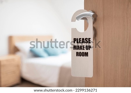 Please make up room sign on hotel room or apartment door with bedroom and bed in background