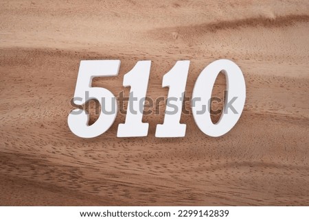 White number 5110 on a brown and light brown wooden background.