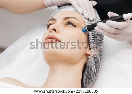 View of doctor cosmetologist doing anti aging procedure in cosmetology office. Satisfied woman in disposable hat lying on couch and relaxing. Working with Apparatus. Royalty-Free Stock Photo #2299188505
