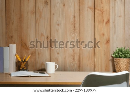 Simple workplace with books, cup of coffee, pencil holder and houseplant on wooden table. Copy space for your text.