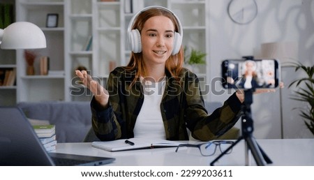 Smiling satisfied successful skilled woman blogger which recording video for internet spectators and applauses in modern living room. Royalty-Free Stock Photo #2299203611