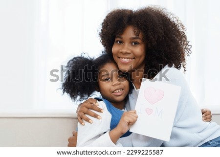 Lovely cute little girl gives mother her drawing post card in the international Mother's Day, American - African black ethnic family portrait. International Mother's Day concept.