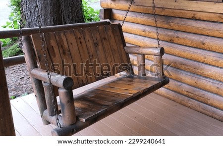 Brown log cottage with log swing on front porch in the woods.  Picture yourself here sitting in the swing in the woods with a friends having a conversation.  