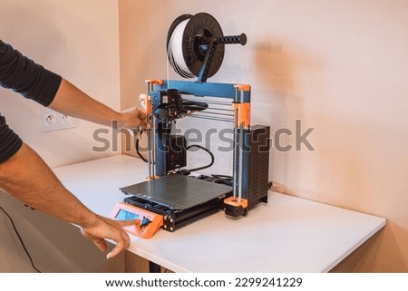 Technological hi-teg tool for making new things. A black and red 3D printer at work. The object is created by laying down continuous layers of material in additive processes.. Royalty-Free Stock Photo #2299241229