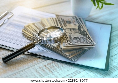 Magnifying glass and money on wooden background, Business Concept.