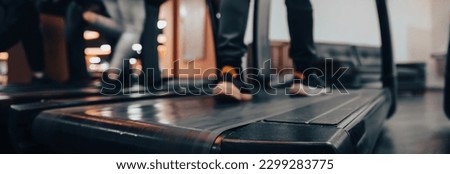 blurred image of young man and woman running on treadmills in gym
