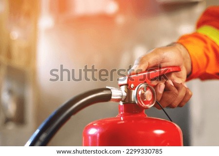 hand presses the trigger fire extinguisher available in fire emergencies conflagration damage background. Safety