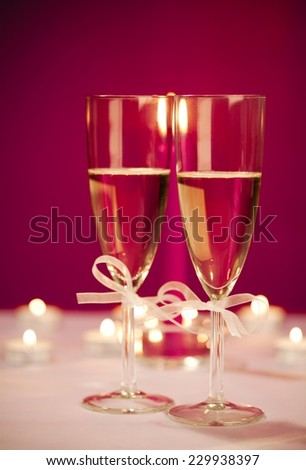 Close up of two champagne glasses surrounded by Christmas decoration and candles
